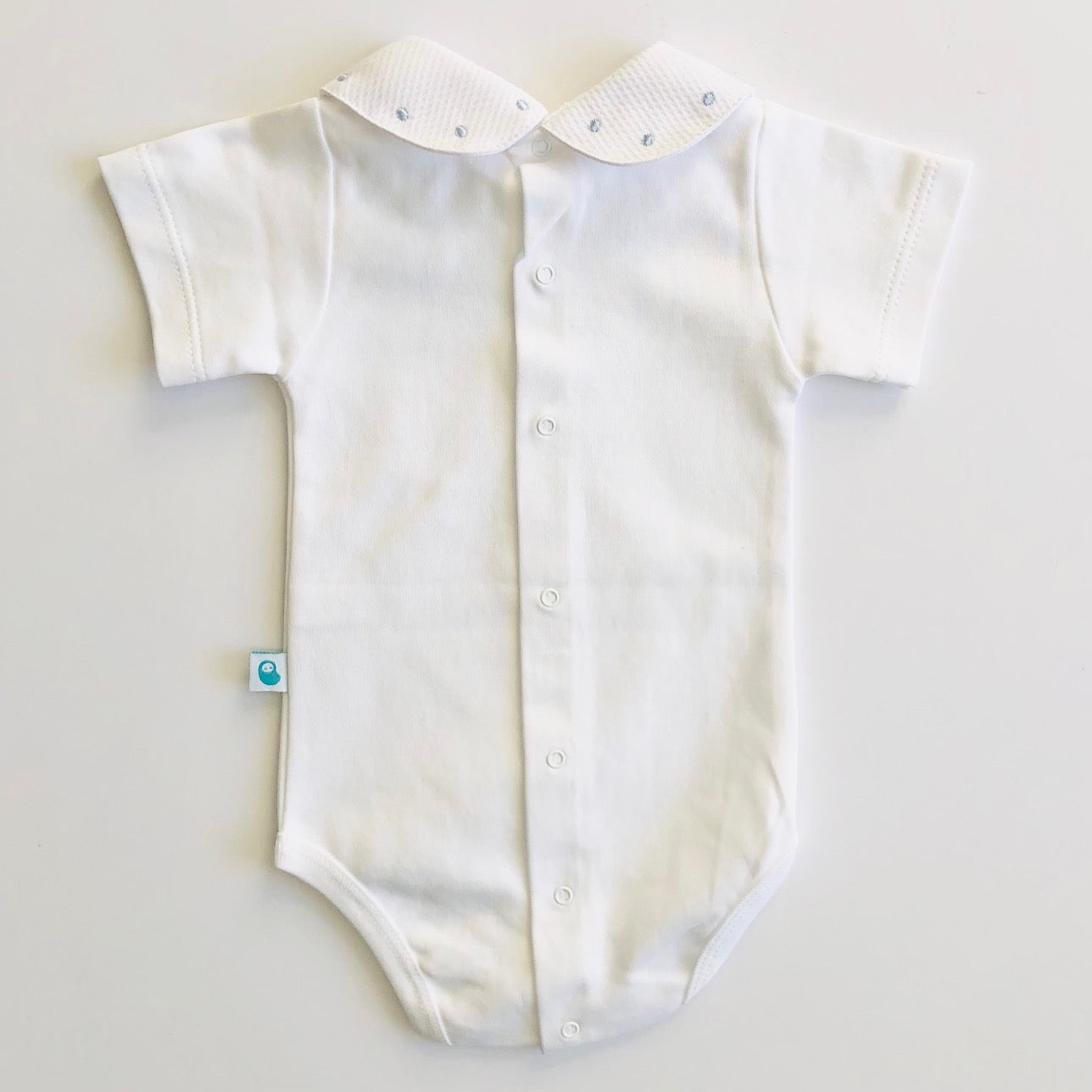 White baby vest with blue spot collar. Back view