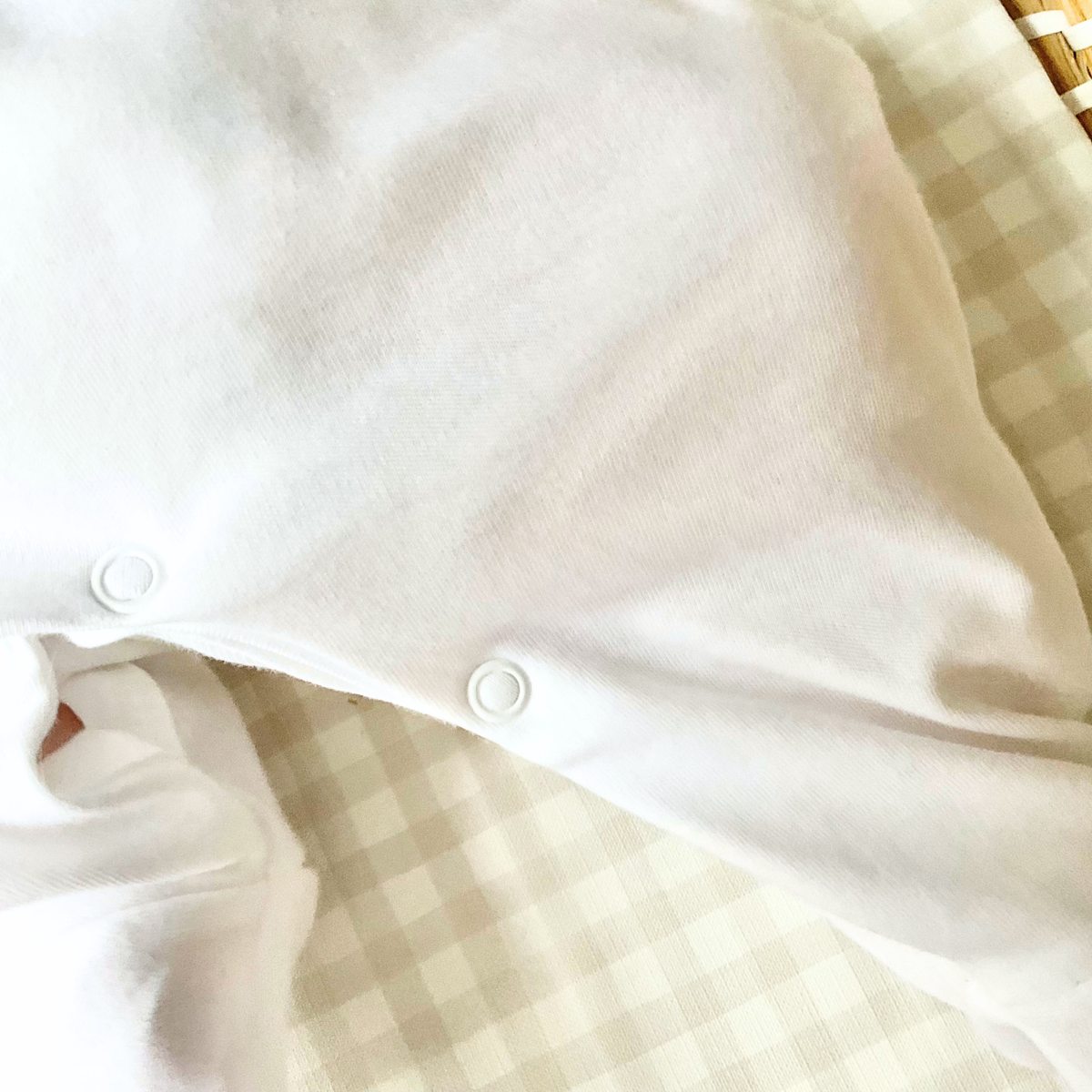 Close-up shot to show the popper under-leg fastening of a baby Sleepsuit