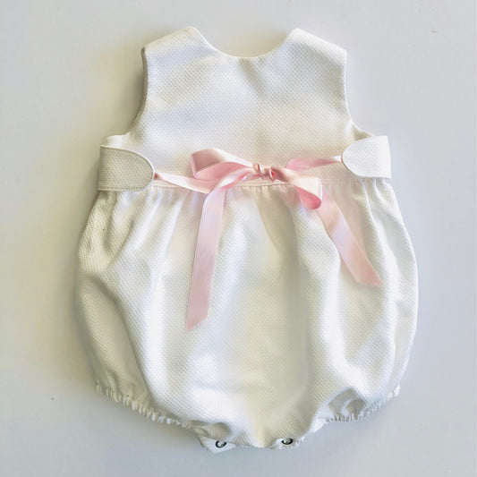 White romper with pink ribbon bow. Front view