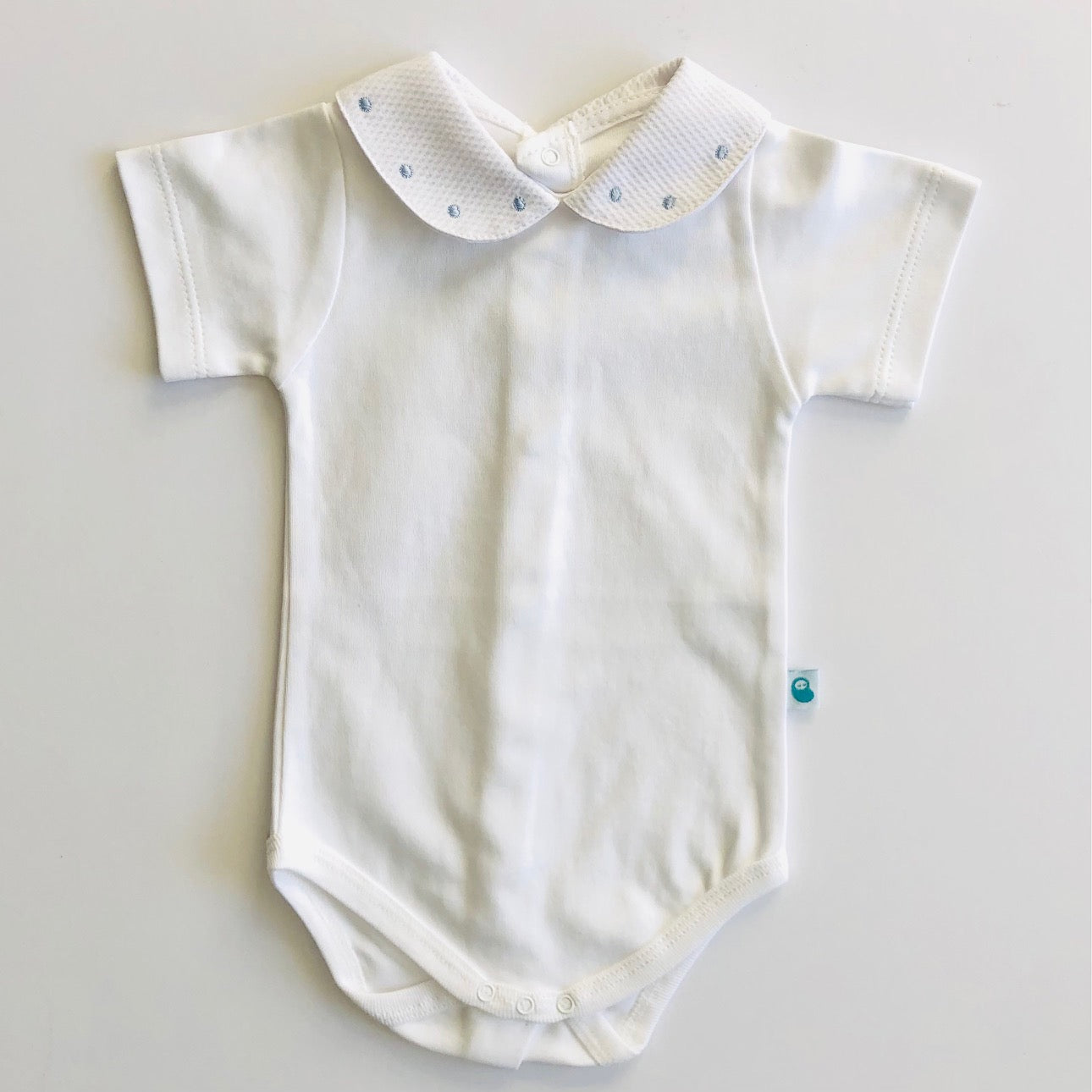 White baby vest with blue spot collar. Front view