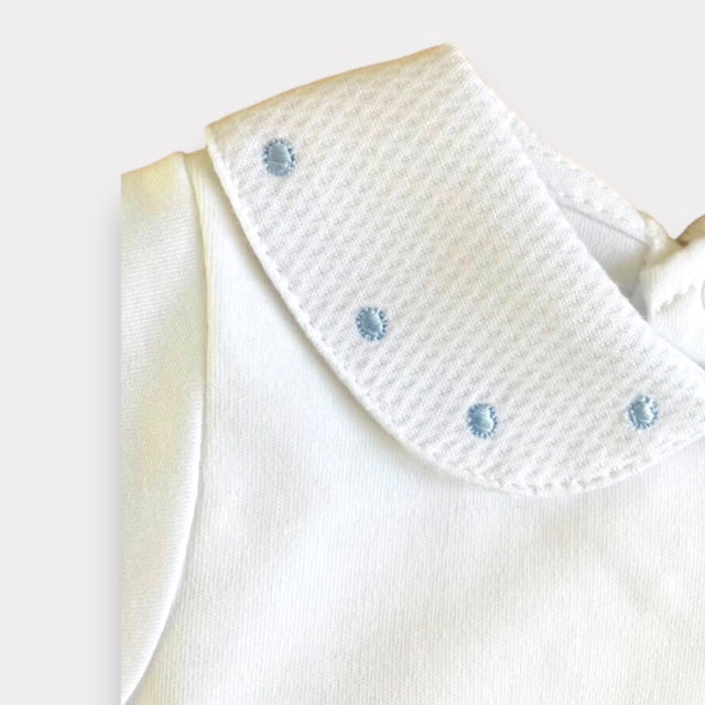 White baby vest with blue spot embroidery on the collar. Close up view of collar